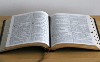 Bíblia aberta sobre uma mesa mostrando vários versículos da bíblia.
